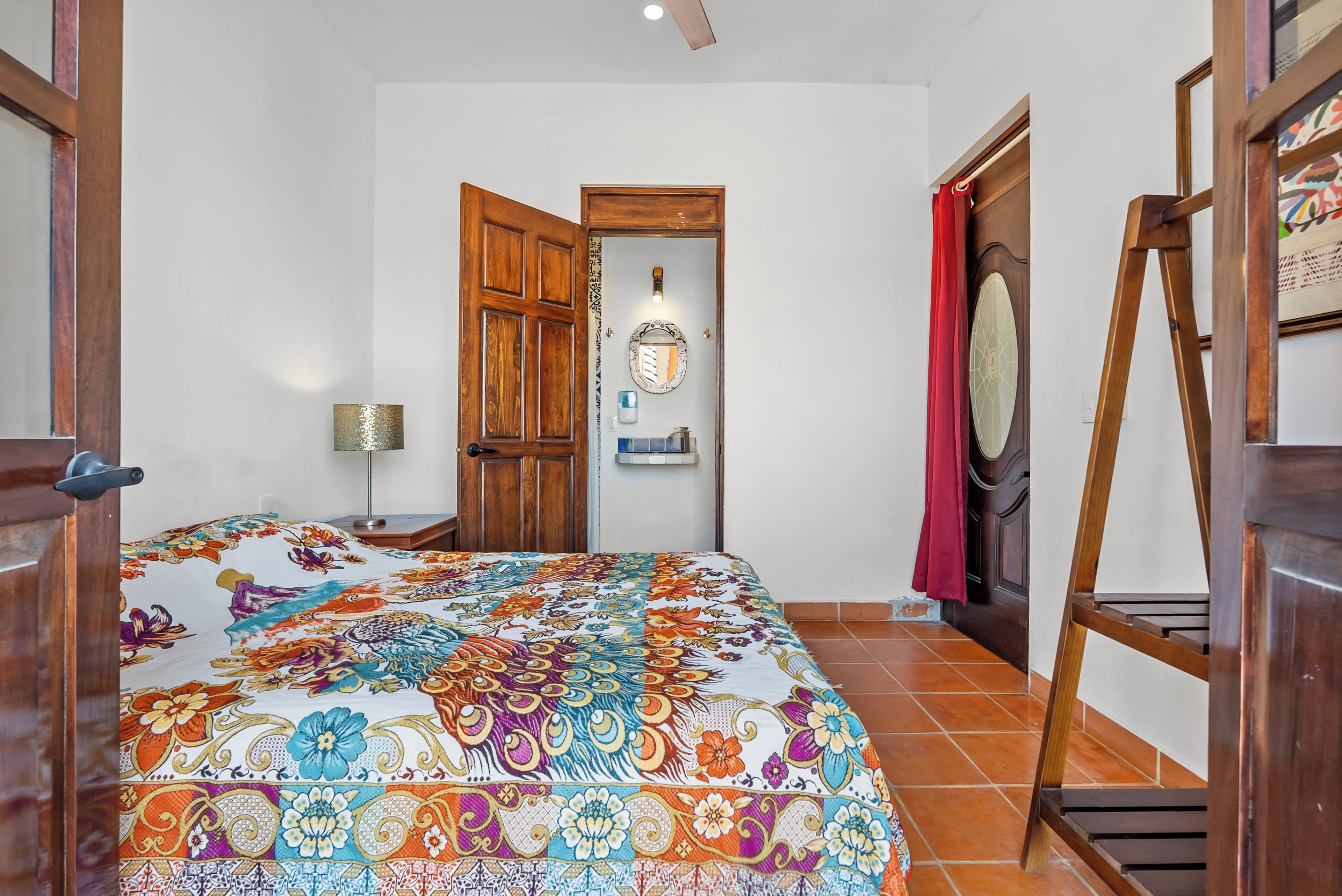 A bedroom with a bed, wooden door, and a ladder.