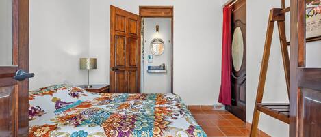 A bedroom with a bed, wooden door, and a ladder.