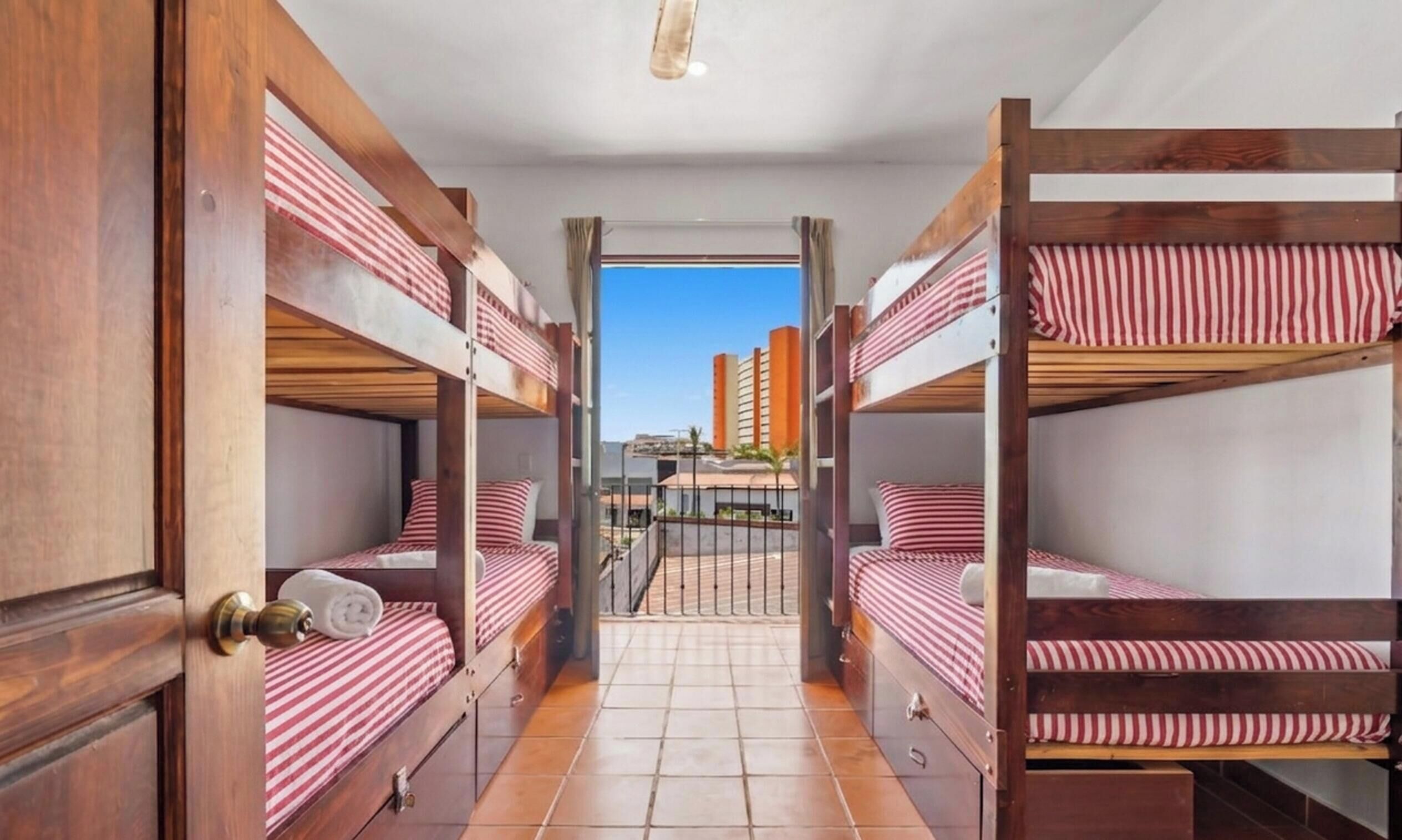 A corridor with bunk beds, wooden doors, and a tiled floor.
