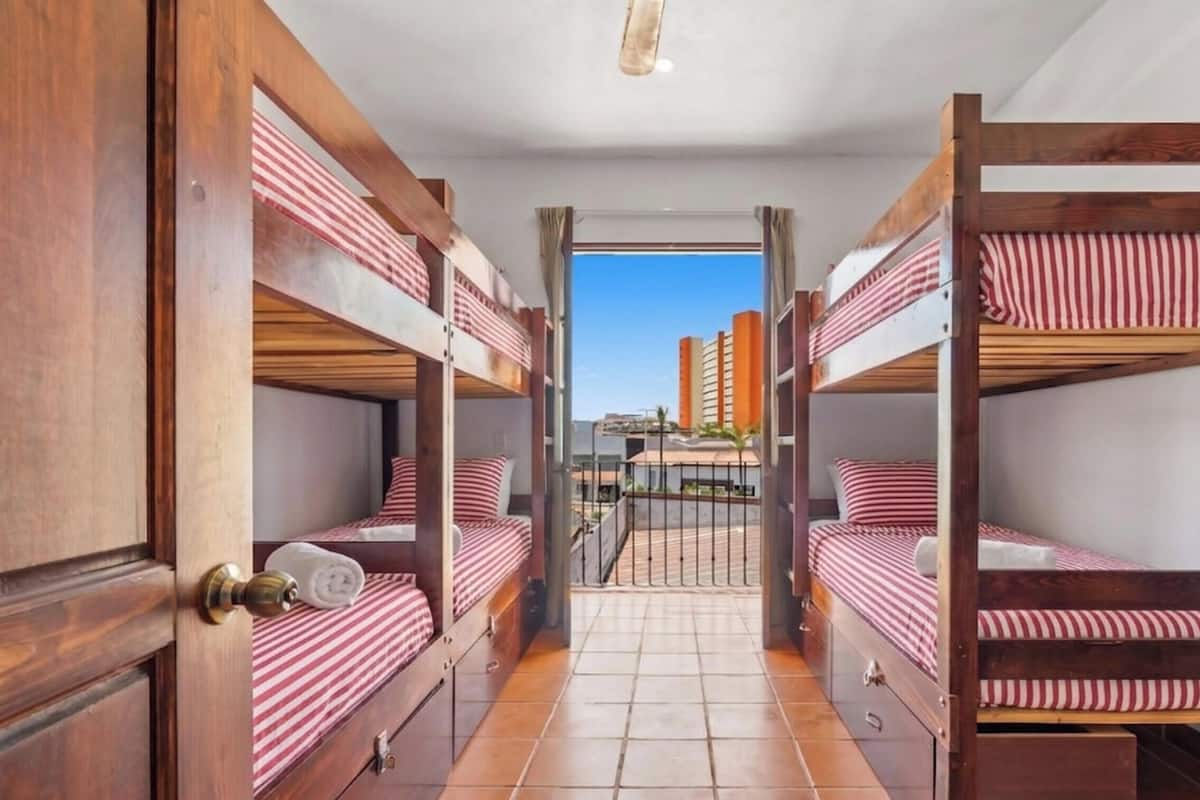 Un pasillo con literas, puertas de madera y piso de baldosas.