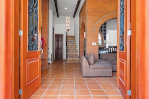Un amplio salón con sofá, una escalera de baldosas con diseño y una pared de ladrillo.