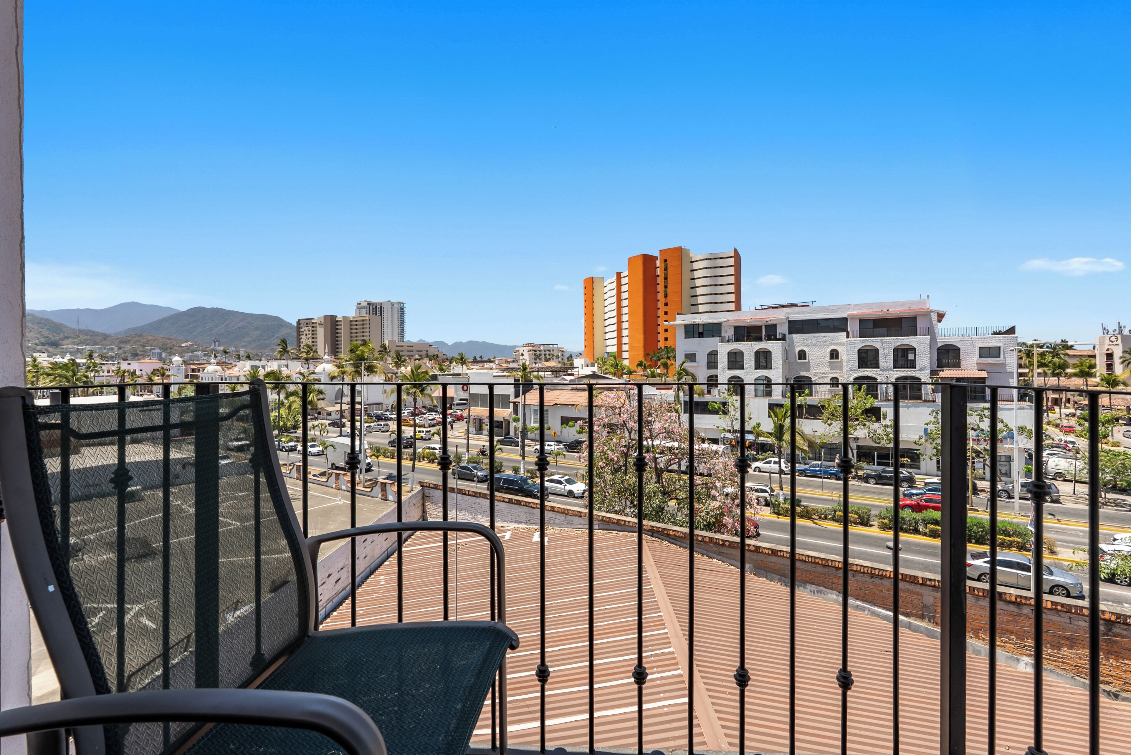 Un balcón con vistas a un paisaje urbano, que incluye edificios y una calle.