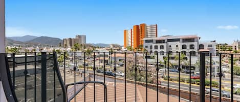 Un balcón con vistas a un paisaje urbano, que incluye edificios y una calle.