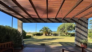 A covered outdoor area with wooden benches and a view of a grassy field.