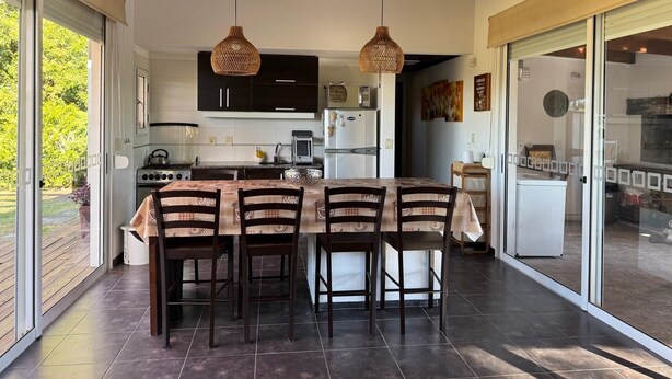 A modern kitchen with dark cabinets, a central island, and hanging wicker pendant lights.
