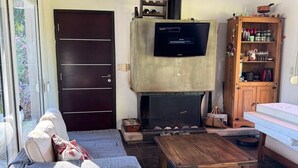A living room with a sofa, coffee table, TV, fireplace, and wooden cabinet.