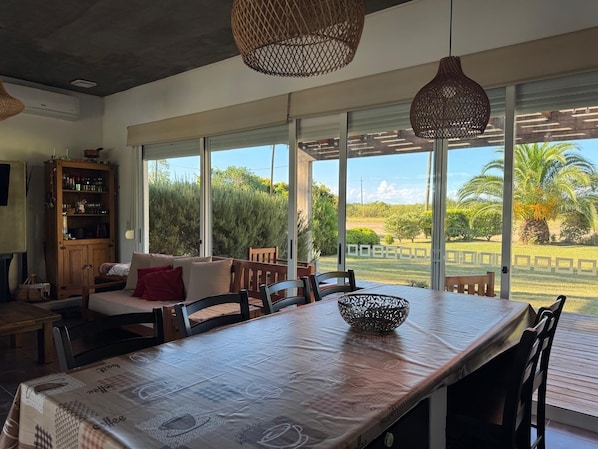A dining area with a table, chairs, and a large window with a view of greenery.