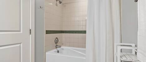 A bathroom with a bathtub, a shower, and a towel rack.