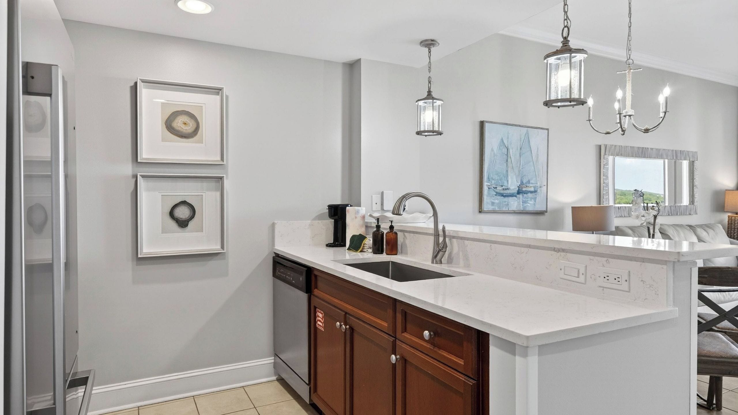 A modern kitchen with a large island, a double sink, and pendant lighting.