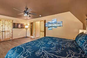 A bedroom with a bed, a ceiling fan, wooden doors, and a painting on the wall. - Peaceful 3BR w/Hot Tub*Fireplace*BBQ*Resort Pools (Gatlinburg)