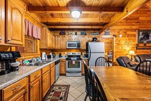 A wooden cabin interior with a kitchen, dining area, and a cozy seating space. - Pet Friendly 2BR w/Hot Tub*Firepit*Jacuzzi*Yard! (Sevierville)