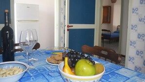 Ruokapöytä, jonka päällä on sininen pöytäliina, viinipullo, viinilaseja ja hedelmäkulho.