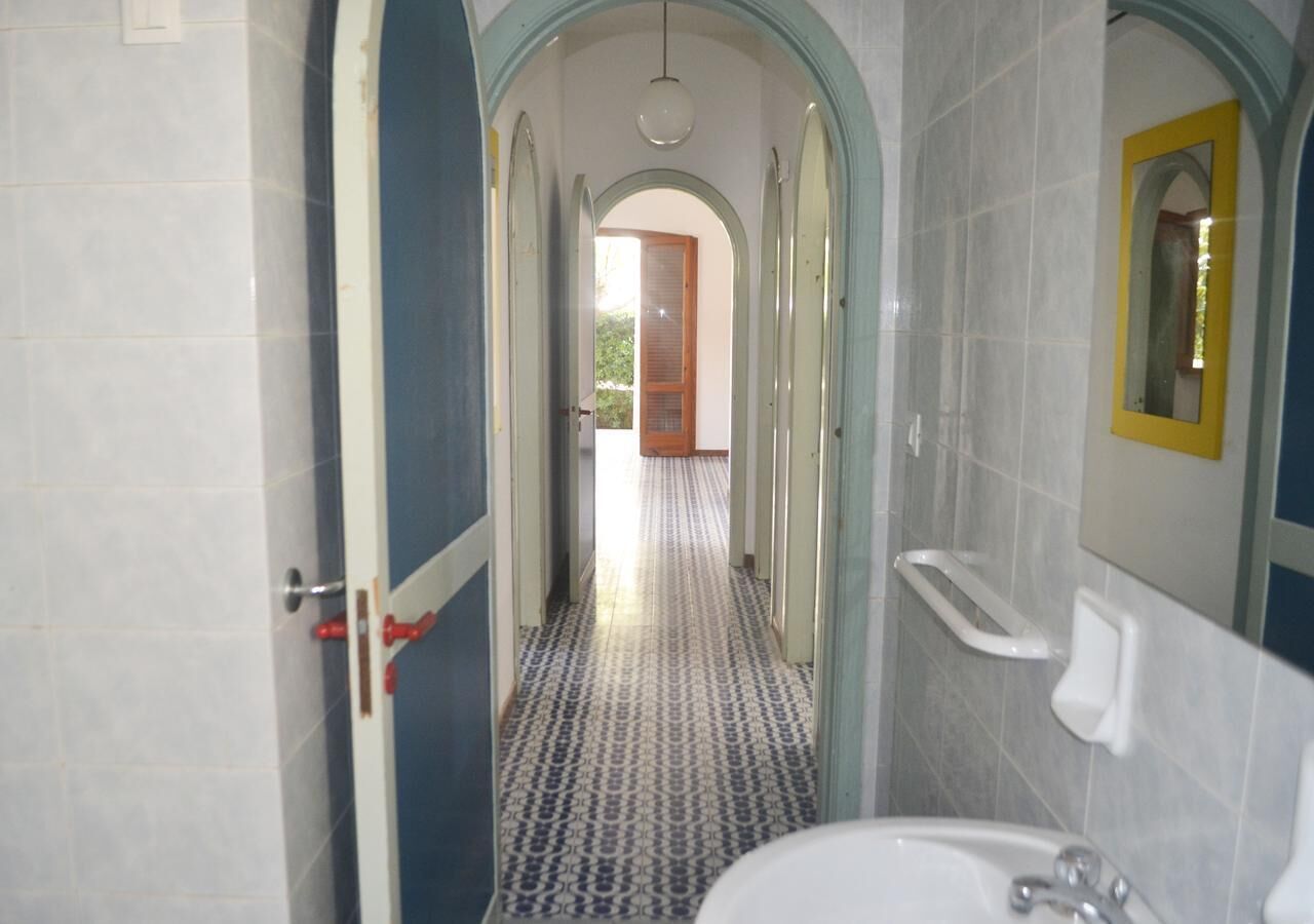 A narrow hallway with a patterned floor leading to a door at the end.