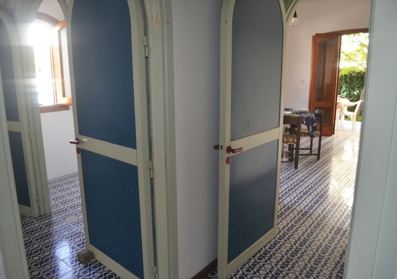 A hallway with patterned floor tiles, a table with chairs, and a door with a blue panel.