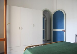 Ein Schlafzimmer mit Bett, Kleiderschrank und zwei Türen.