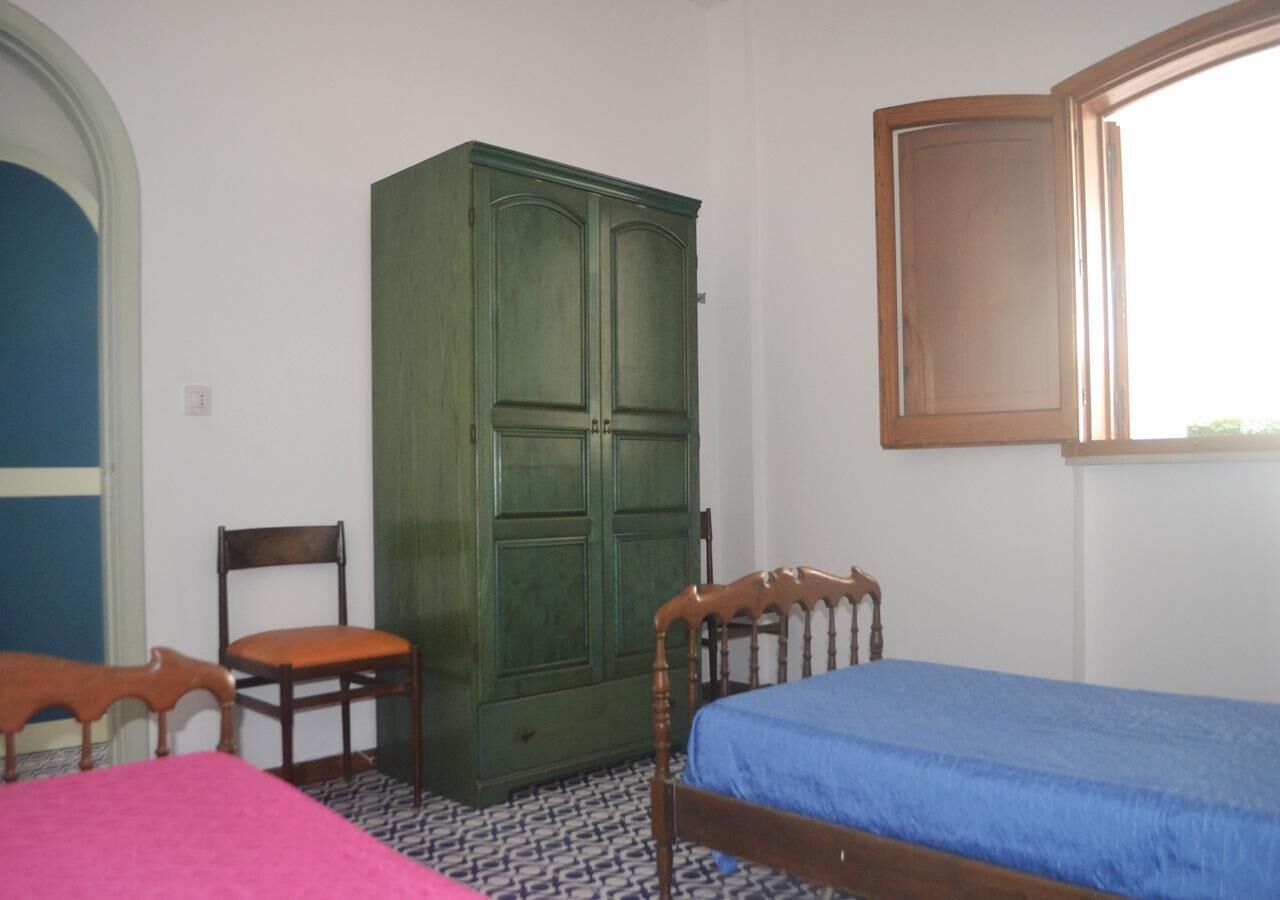 A room with a bed, a chair, a wardrobe, and a window.