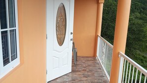 Un balcone con una porta bianca, pavimento in pietra e ringhiera.
