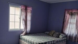 Una camera da letto con un letto, tende, una finestra e un tappeto viola.