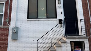 Een meerlaags gebouw met witte bakstenen muren, grote ramen en een zwarte deur.