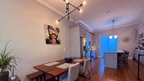 Een moderne keuken met roestvrijstalen apparatuur, een eethoek met een houten tafel en stoelen, en een blauwe accentmuur.
