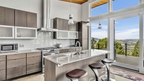 A modern kitchen with a large island, stainless steel appliances, and a view of the countryside. - Trinity Vista by Avantstay Private Dual-zone Spa + Fire Pit + Outdoor Dining + Views Sonoma Wine Country (Glen Ellen)