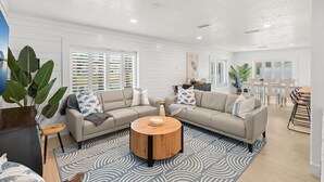A spacious living area with a large sectional sofa, a round coffee table, and a dining table with chairs. - 504 Colony Street (Melbourne Beach)