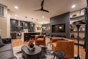 A modern living room with a sofa, two armchairs, a coffee table, and a TV. - Brick Haven / Hot Tub, Cold Plunge & Sauna Vibes (Nashville)