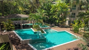 A rooftop pool with a wooden deck, surrounded by lush greenery and palm trees. - Luxury Beachfront Resort & Jungle Wildlife (Quebrada)