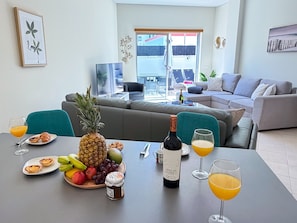 Ein Essbereich mit einem Tisch, der für ein Frühstück gedeckt ist, mit Früchten, Gebäck und Getränken.