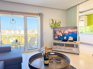 Ein Wohnzimmer mit Fernseher, einer Champagnerflasche und Snacks auf einem Tablett.