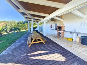 An outdoor patio with a wooden table and benches, a brick pizza oven, and a sink. - Terras Novas Village Paradise By BeCherish (Albufeira)