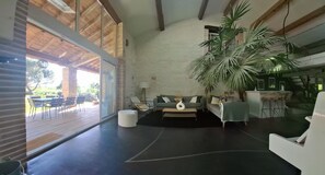 Un espacio habitable amplio con un gran ventanal, un sofá, una mesa de centro y una planta en maceta.
