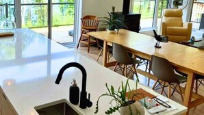 Une cuisine moderne dotée d’un grand îlot central, de luminaires suspendus et offrant une vue sur l’extérieur.