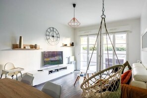 A modern living room with a TV, seating, and a hanging chair. - Cosy F3 with private terrace - Plessis-Robinson - 20 min. Paris (Le Plessis-Robinson)