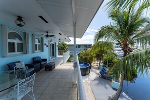 A covered outdoor area with seating, a hot tub, and a palm tree.