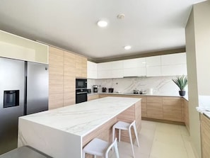 Eine moderne Küche mit einer Marmorinsel, Edelstahlgeräten und Holzschränken.
