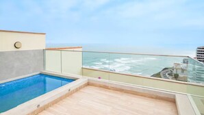 A rooftop pool with a glass balustrade, a clear view of the ocean, and a cityscape in the background. - Penthouse Pacific Luxury King 6BR/5BA Larcomar (Miraflores)