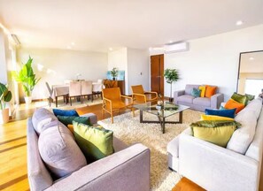 Ein modernes Wohnzimmer mit Sofas, Sesseln, einem Couchtisch und einem Essbereich.