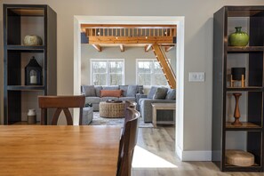 Ein Wohnzimmer mit einem Holzesstisch, zwei Sofas, einer Treppe und eingebauten Regalen.
