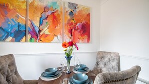 Ein Esstisch mit blauem Geschirr, Besteck und einer Blumenvase.