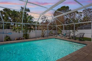 A swimming pool with a clear blue water, surrounded by a white metal fence, and palm trees in the background. - Mermaid Cove | Backyard Dream: Putting Green, Pool (Siesta Key)