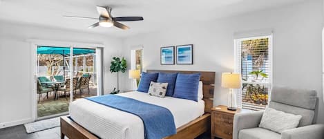 A bedroom with a bed, a ceiling fan, a nightstand, a chair, and a view through a window.