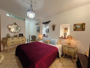 A bedroom with a large bed, a chandelier, ornate furniture, and wall-mounted decorations. - House of Gattopardo Cefalù (Cefalù)