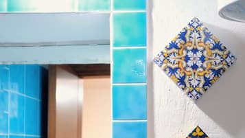 A bathroom with blue tiles, a mirror, and decorative wall tiles.