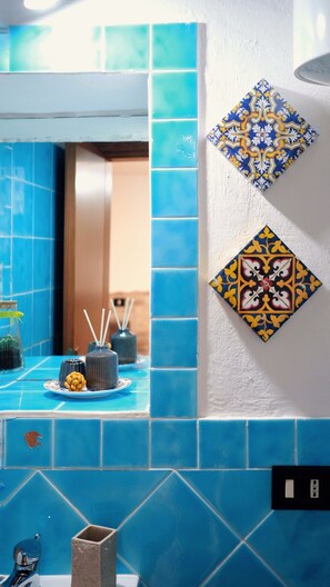 A bathroom with blue tiles, a mirror, and decorative wall tiles. - House of Gattopardo Cefalù (Cefalù)