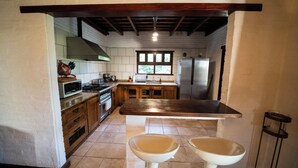 A kitchen with wooden cabinets, a stove, a microwave, and a refrigerator. - La Soleada Polo Ranch (Mercedes)