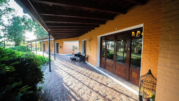 A covered outdoor patio with brick flooring, a wooden ceiling, and a door with glass panels. - La Soleada Polo Ranch (Mercedes)