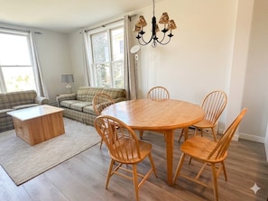 Ein Essbereich mit Holztisch und Stühlen, einer Couch, einer Lampe und einem Kronleuchter.