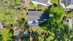 Vista aérea de una casa con patio cercado, piscina y zona de patio con mobiliario exterior.
