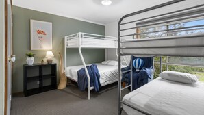 A bunk bed room with a framed picture on the wall, a bedside table with a lamp, and a window with a view of greenery. - Velora Rye Pet Friendly Home (Rye)